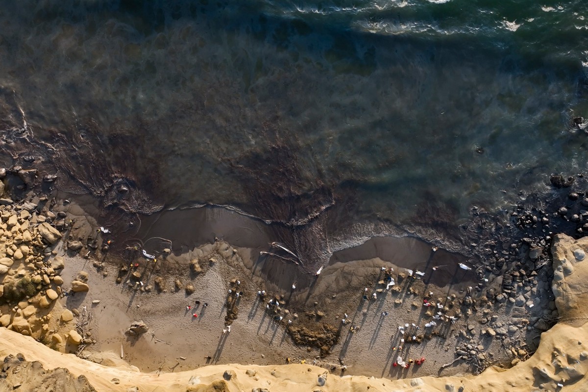 Handout picture released by NGO Coast 2 Coast Movement showing an aerial view of workers cleaning up Las Capullanas beach, after an oil spill in the Lobitos district in Piura, northern Peru on December 22, 2024. Photo by Nicolas LANDA TAMI / Coast to Coast Movement / AFP