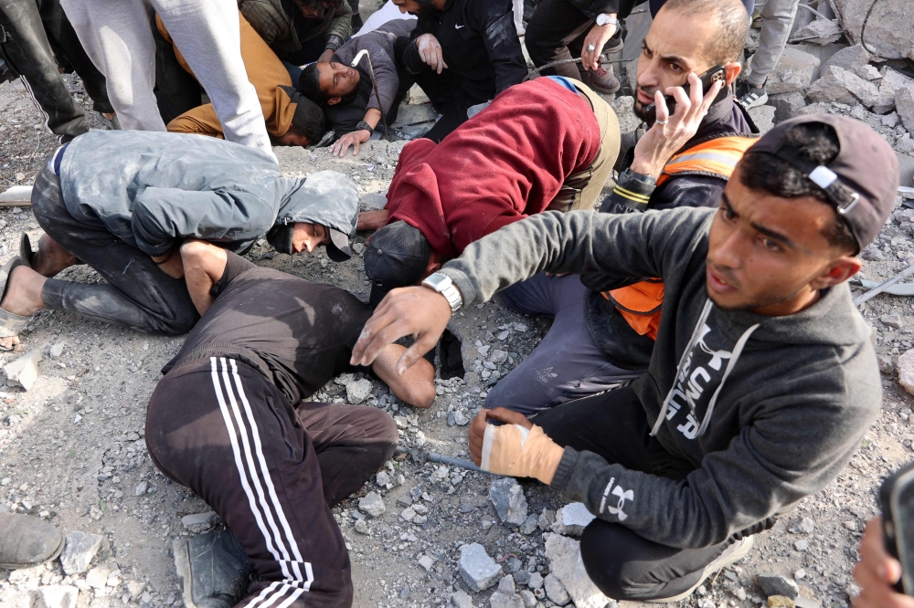 Civilians look for survivors at the site of an Israeli strike in a residential area in the Tuffah neighbourhood, east of Gaza City, on December 26, 2024. (Photo by Omar Al-Qattaa / AFP)