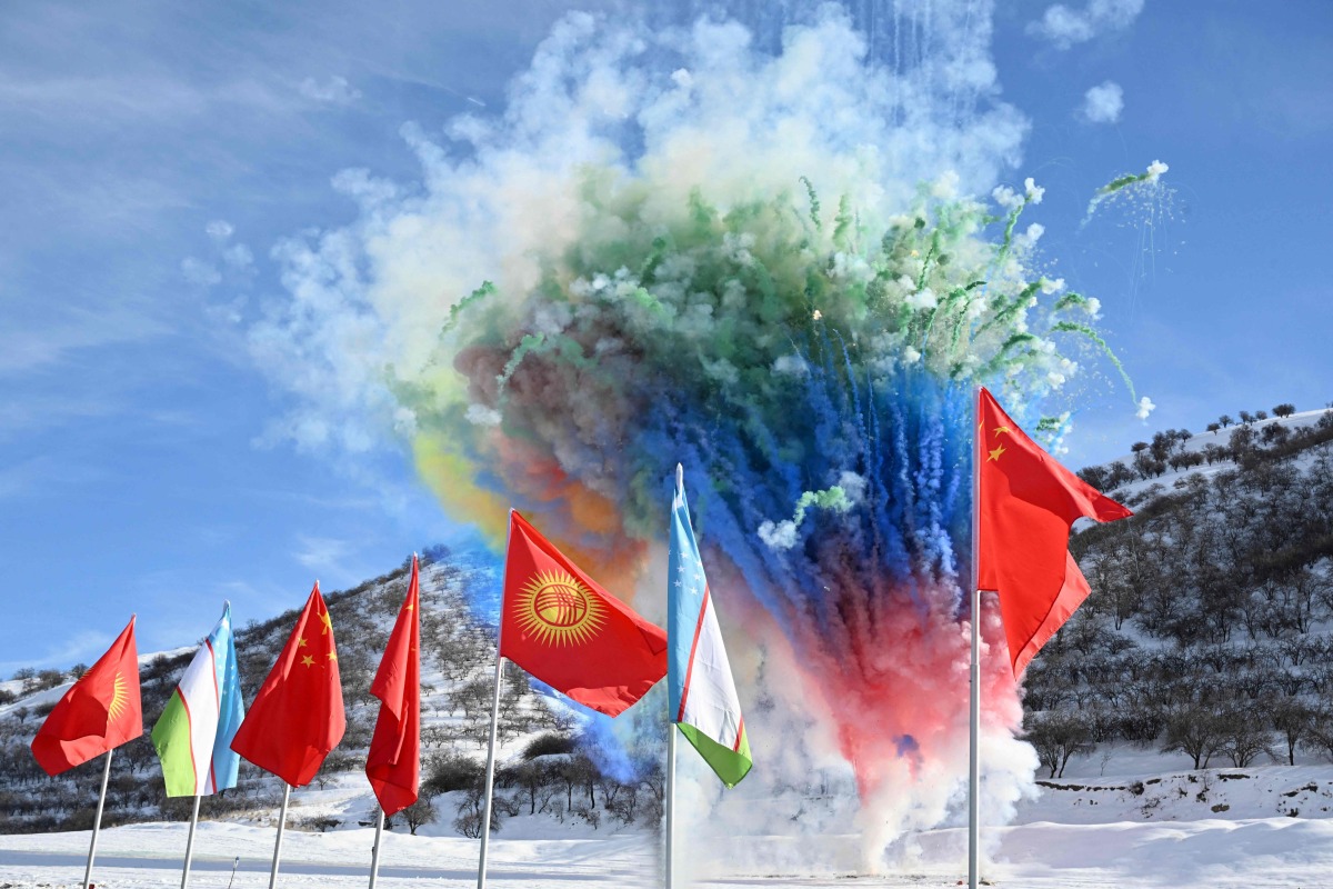 In this handout picture taken and released by the Kyrgyz presidential press office on December 27, 2024, fireworks explode behind state flags during the commencement ceremony of the China-Kyrgyzstan-Uzbekistan railway project in the settlement of Tash-Kitchu. (Photo by Handout / KYRGYZ PRESIDENTIAL PRESS OFFICE / AFP)