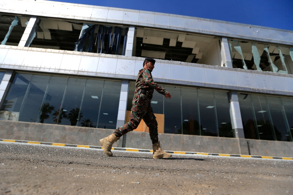 A member of Yemen's security forces walks past a damaged building at Sanaa international airport on December 27, 2024, following Israeli strikes at the site the previous day. (Photo by Mohammed Huwais / AFP)