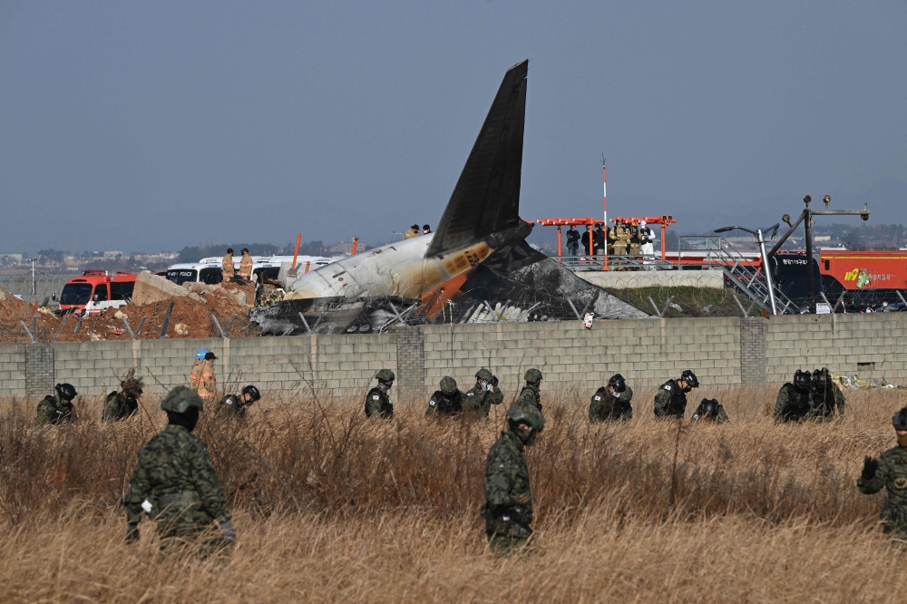 South Korean soldiers search for missing passengers near the wreckage of a Jeju Air Boeing 737-800 series aircraft after the plane crashed and burst into flames at Muan International Airport in South Jeolla Province on December 29, 2024. (Photo by Jung Yeon-Je / AFP)