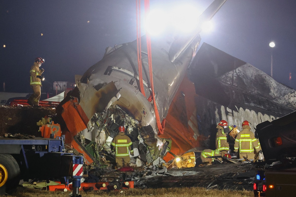 Firefighters and rescue personnel work near the scene where a Jeju Air Boeing 737-800 series aircraft crashed and burst into flames at Muan International Airport in South Jeolla Province, some 288 kilometers southwest of Seoul on December 29, 2024. (Photo by YONHAP / AFP) 