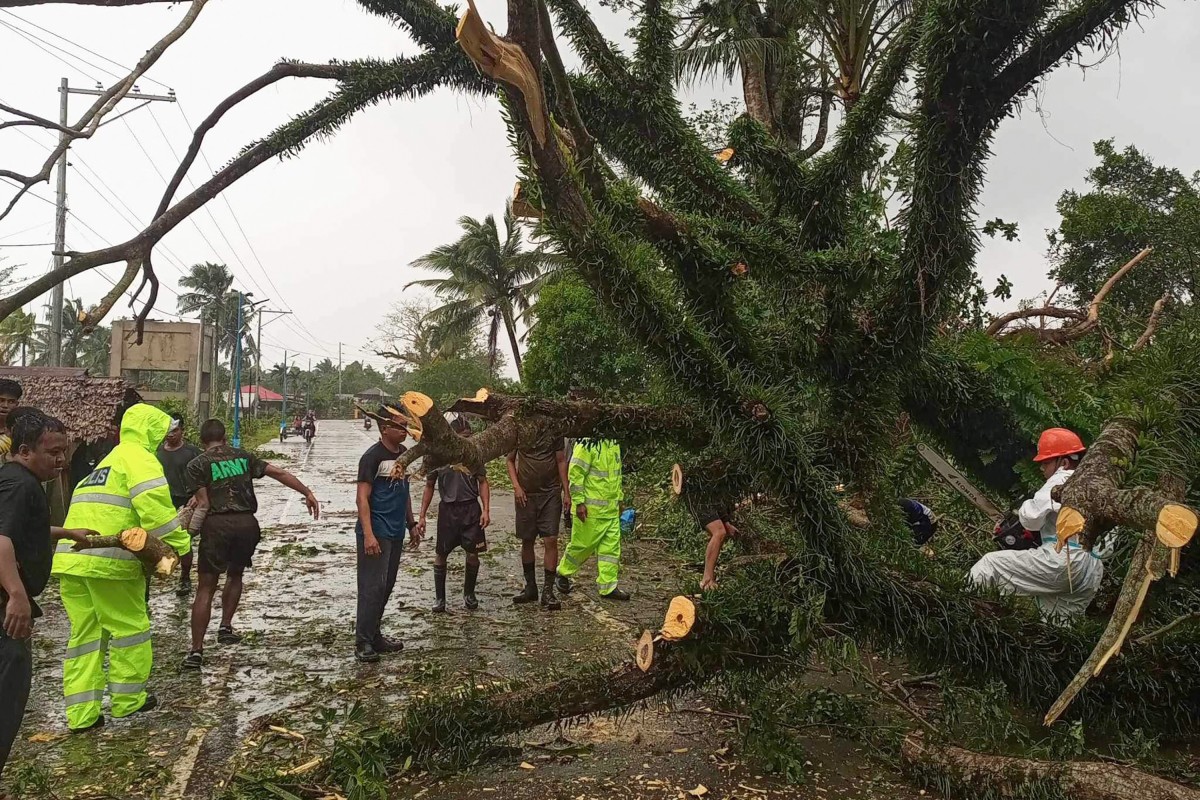 This handout photo taken on November 11, 2024 and received from the Casiguran Municipal Risk Reduction Management Office (MDRRMO) shows government workers removing a fallen tree on a highway in Casiguran, Aurora province, after Typhoon Toraji hit the nation's northeast coast. Photo by Handout / Casiguran Municipal Risk Reduction Management Office / AFP

