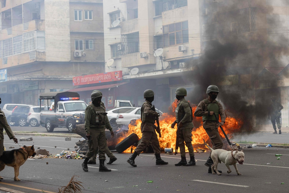 (FILES) Anti-riot police officers with their dogs walk down Eduardo Mondlane Avenue past burning barricades made by protesters in Maputo November 7, 2024. (Photo by ALFREDO ZUNIGA / AFP)
