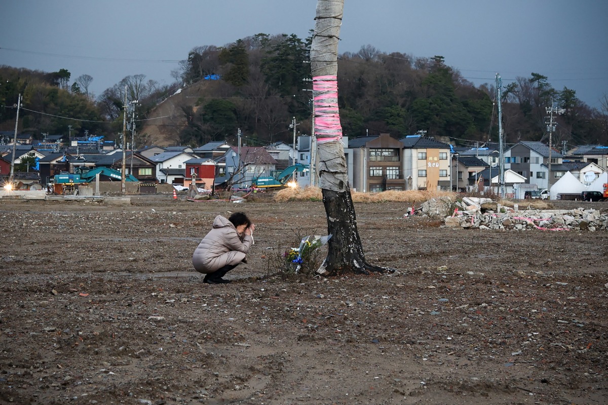 A woman prays near the former tourist spot of 