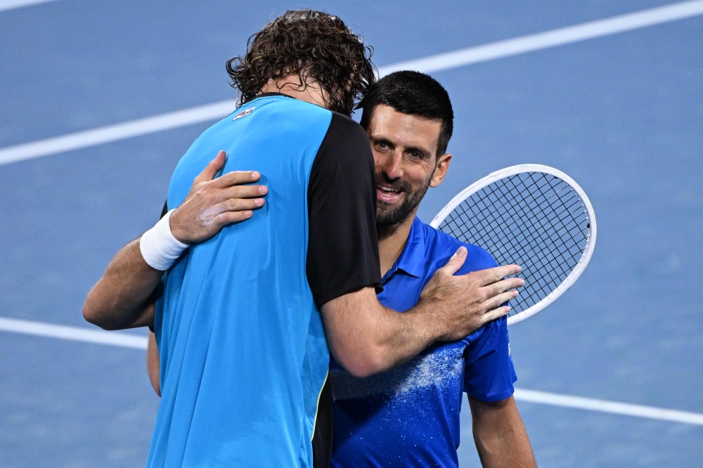 Winner Reilly Opelka of the United States (left) and Serbia's Novak Djokovic embrace at the net after their men's singles quarter-final match at the Brisbane International tennis tournament in Brisbane on January 3, 2025. (Photo by William West / AFP)