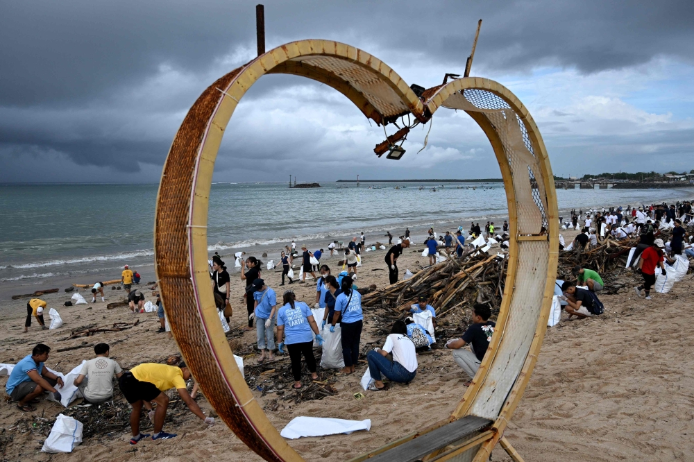 Participants and volunteers remove plastic waste and other garbage washed ashore at a beach in Kedonganan Badung regency, Indonesia's Bali island on January 4, 2025. (Photo by Sonny Tumbelaka / AFP)