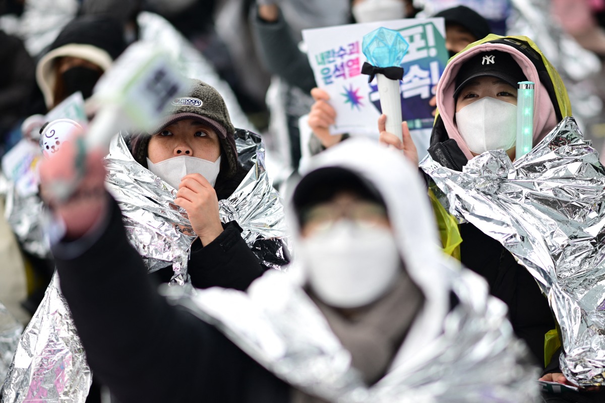 Demonstrators wear thermal blankets during a rally against impeached South Korea President Yoon Suk Yeol near his residence in Seoul on January 5, 2025. Photo by Philip FONG / AFP.