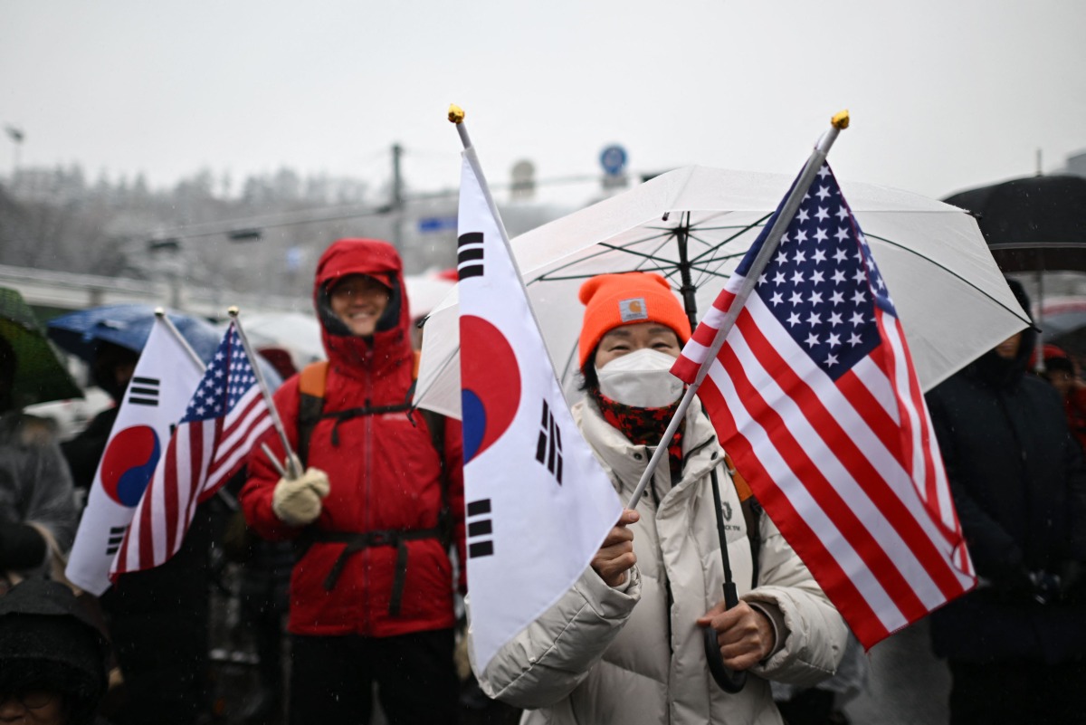 Supporters of impeached South Korea president Yoon Suk Yeol hold US and South Korean flags as they take part in a rally near his residence as snow falls in Seoul on January 5, 2025. (Photo by Philip FONG / AFP)
