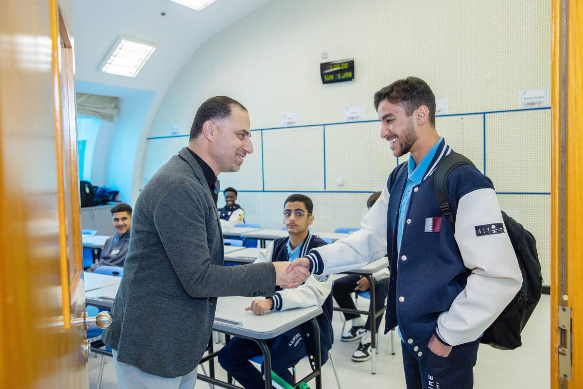 A teacher welcomes a student in the classroom. 