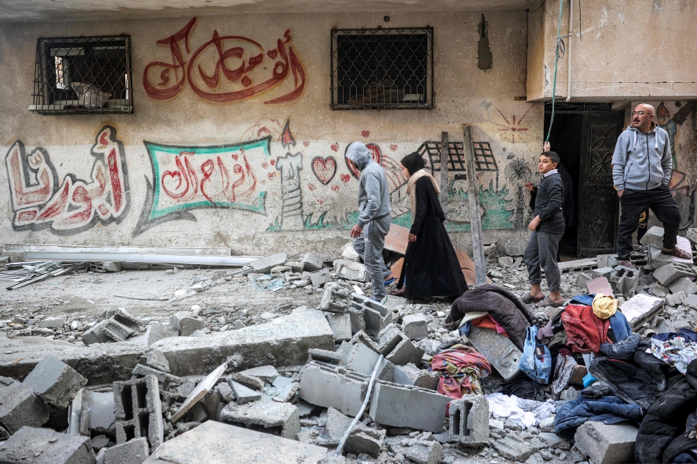 Rubble and salvaged clothes are piled in a street outside an apartment building hit by Israeli bombardment in the Bureij camp for Palestinian refugees in the central Gaza Strip on January 7, 2025. (Photo by Eyad Baba / AFP)