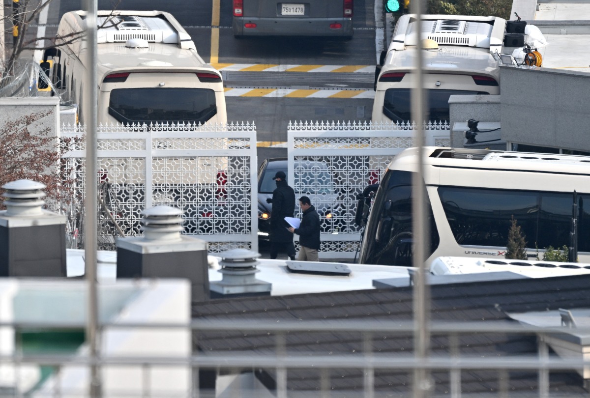 Security personnel check vehicles at the entrance gate of the presidential residence of impeached South Korea President Yoon Suk Yeol, as seen from a hill in Seoul on January 8, 2025. (Photo by Jung Yeon-je / AFP)