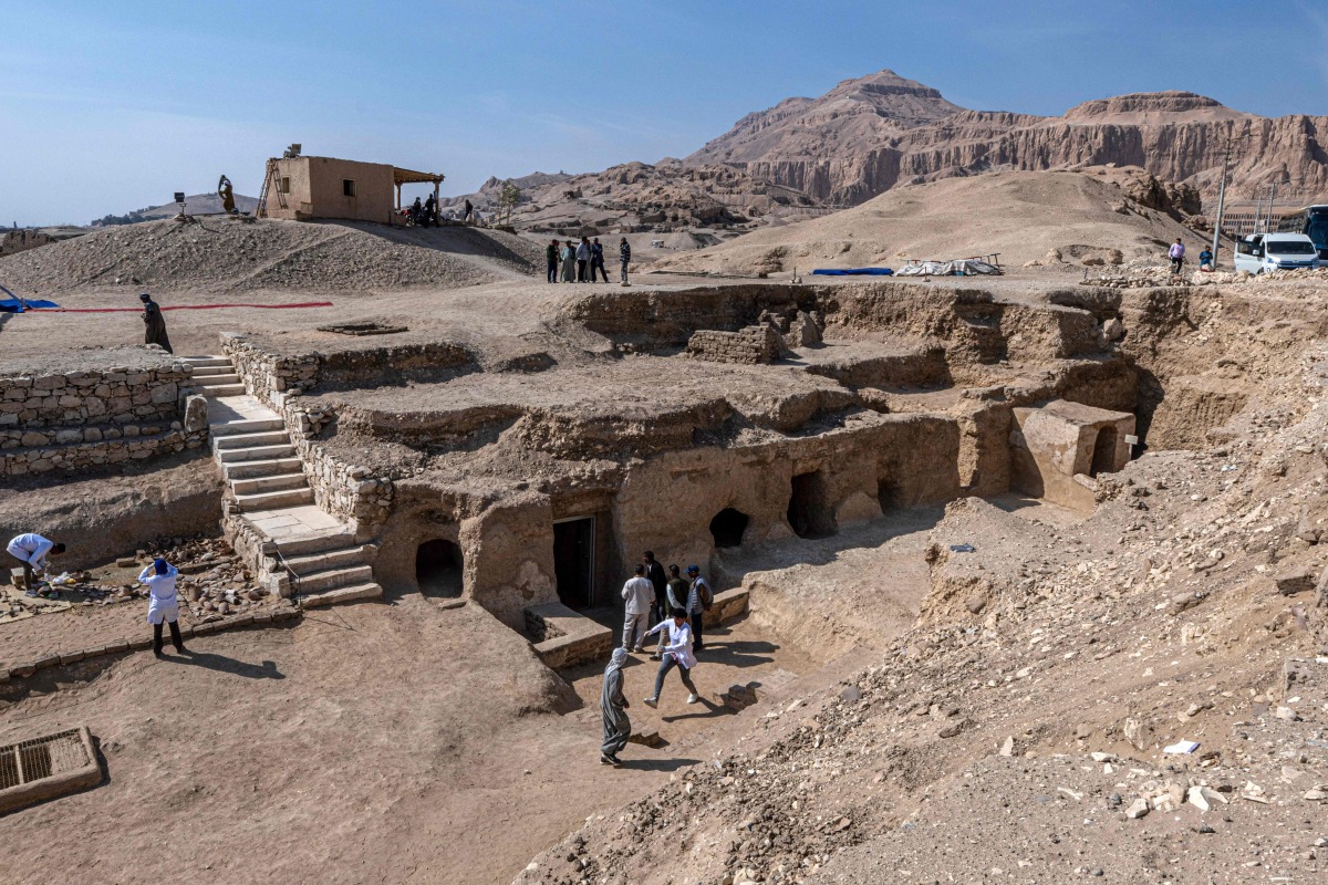 Visitors walk around a dig showcasing the tomb of an overseer of the palace of Queen Teti Sheri, during a media event to announce new discoveries by an Egyptian archaeological mission in Deir El-Bahari on the Nile's west bank in Luxor on January 8, 2025. (Photo by Khaled DESOUKI / AFP)