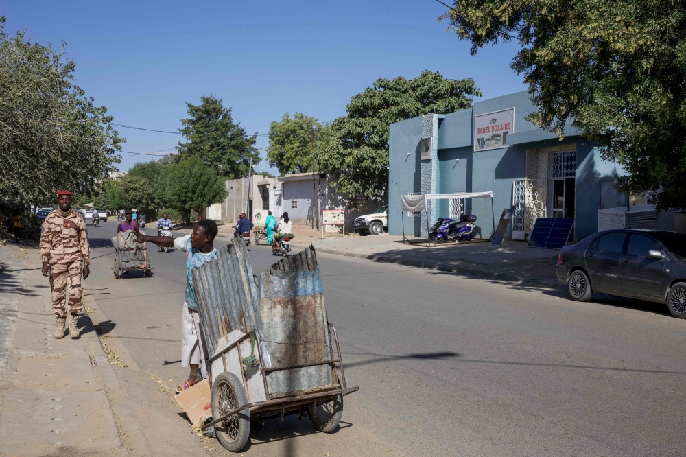 A Chadian soldier (L) looks on as a man with a cart gestures on a street in the Djambal Bahr district of N'Djamena on January 9, 2025. (Photo by Joris Bolomey / AFP)