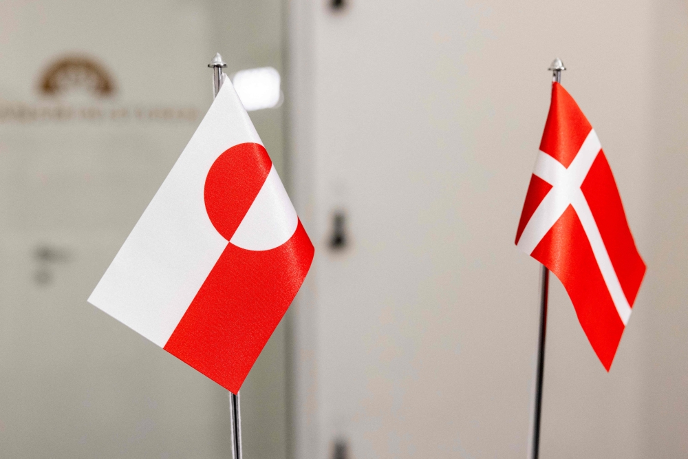 The Greenlandic (L) and Danish flags are pictured at the Ministry of Finance in Copenhagen on January 8, 2025. (Photo by Nikolai Linares / Ritzau Scanpix / AFP) 