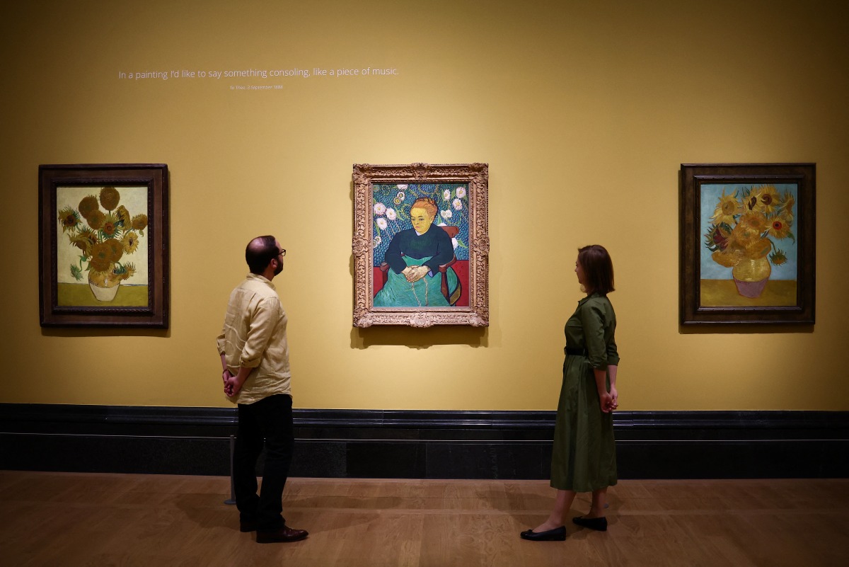 Visitors look at (from L) three paintings made by late Dutch artist Vincent Van Gogh 