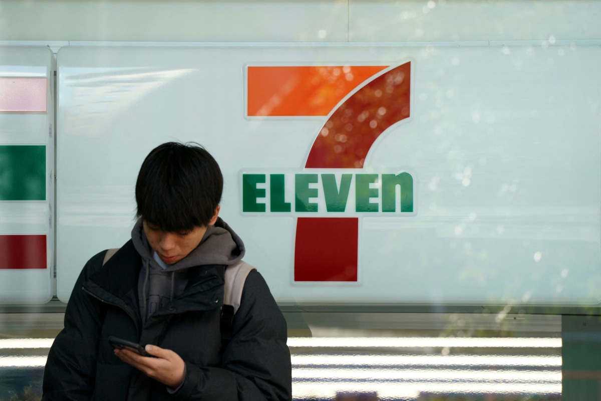 A man stands in front of a 7-Eleven convenience store along a street in central Tokyo on January 9, 2025. (Photo by Kazuhiro NOGI / AFP)