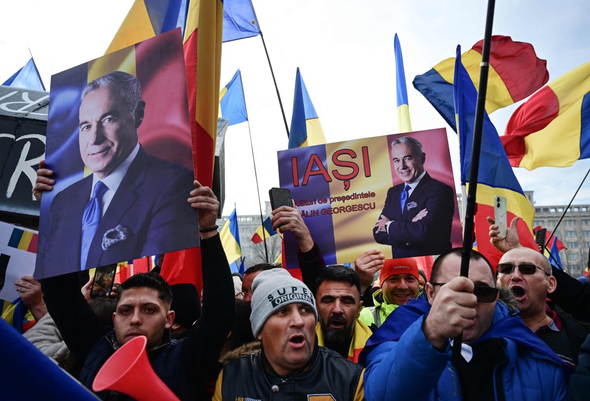 People wave Romanian flags and hold portraits of far-right presidential candidate Calin Georgescu during a protest in front of Romania's Constitutional Court in Budapest on January 10, 2024. (Photo by Daniel MIHAILESCU / AFP)