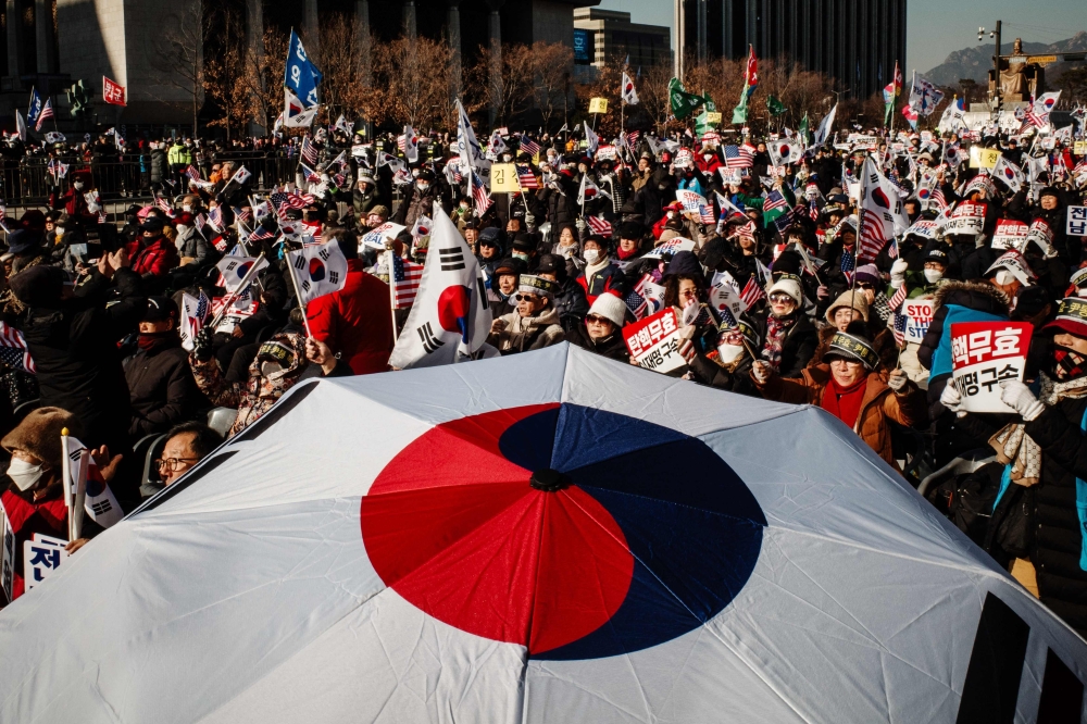 Supporters of impeached South Korea president Yoon Suk Yeol wave flags and shout slogans during a rally in Gwanghwamun in Seoul on January 11, 2025. (Photo by Anthony Wallace / AFP)