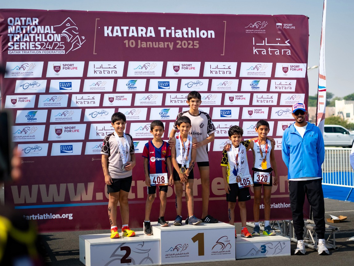 Young athletes celebrate on the podium at the conclusion of the Katara Triathlon Championship.