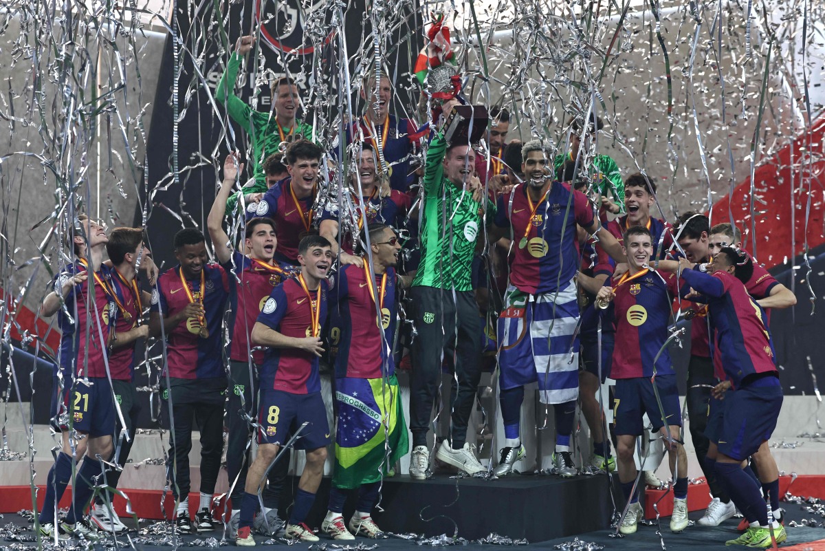 Barcelona's players celebrate with the trophy after winning the Spanish Super Cup final football match between Real Madrid and Barcelona at the King Abdullah Sport City in Jeddah on January 12, 2025. (Photo by FADEL SENNA / AFP)
