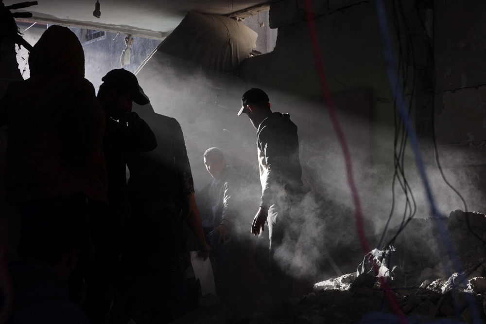 People search for their belongings amid the rubble of buildings destroyed in Israeli airstrikes in Gaza City on January 13, 2025. (Photo by Omar Al Qattaa / AFP)