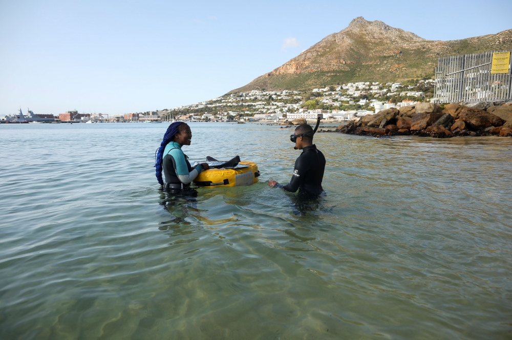 Free diver Zandile Ndlovu encourages a township youth to explore the marine world off Simonstown, near Cape Town, South Africa, August 22, 2021. Reuters/Mike Hutchings