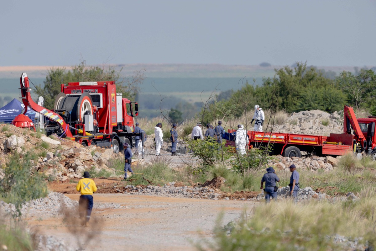 Rescuers and South African Police Service (SAPS) officers carry remains in blue body bags during a rescue operation to retrieve illegal miners from an abandoned gold shaft in Stilfontein on January 13, 2025.Photo by Christian Velcich / AFP