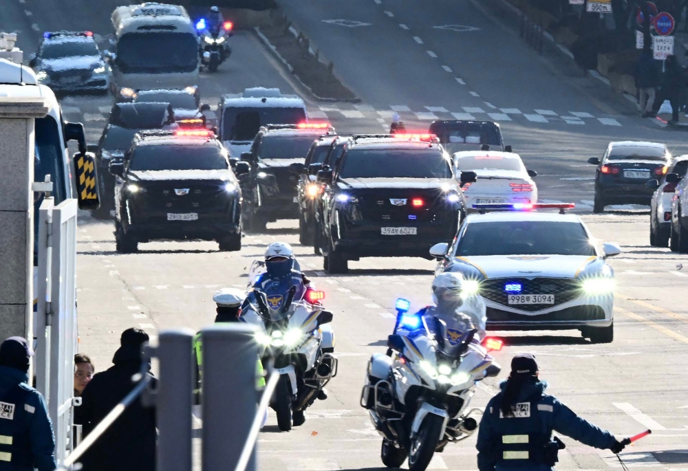 A motorcade carrying impeached South Korea President Yoon Suk Yeol arrives at the complex building housing the Corruption Investigation Office for High-ranking Officials (CIO) in Gwacheon on January 15, 2025, after Yoon was arrested over his failed martial law bid. (Photo by Korea Pool / AFP) 