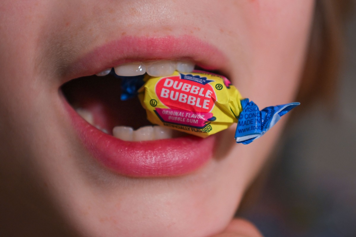 A boy holds a wrapped Dubble Bubble Bubble Gum candy in his mouth, a product that uses Red Dye # 3, in this illustration photograph on December 27, 2024. Photo by ROBERTO SCHMIDT / AFP