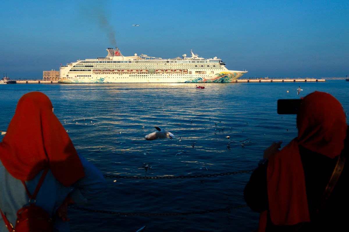 Women take pictures of a cruise ship docked in the Old Doha Port on December 26, 2024. (Photo by KARIM JAAFAR / AFP)

