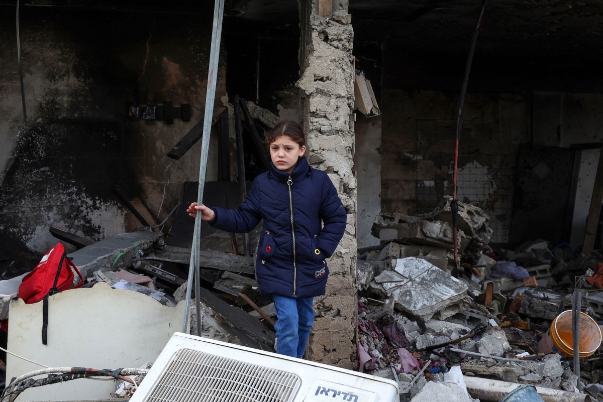 The daughter of a man killed during an Israeli air strike the previous day, checks the destruction at the site of the attack, in Jenin's refugee camp in the occupied West Bank, on January 16, 2025. (Photo by Zain JAAFAR / AFP)
