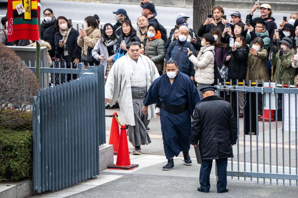 People gather at the entrance of Ryogoku Kokugikan for the arrival of sumo wrestlers during the Grand Sumo Tournament in Tokyo on January 19, 2025. (Photo by Philip Fong / AFP)