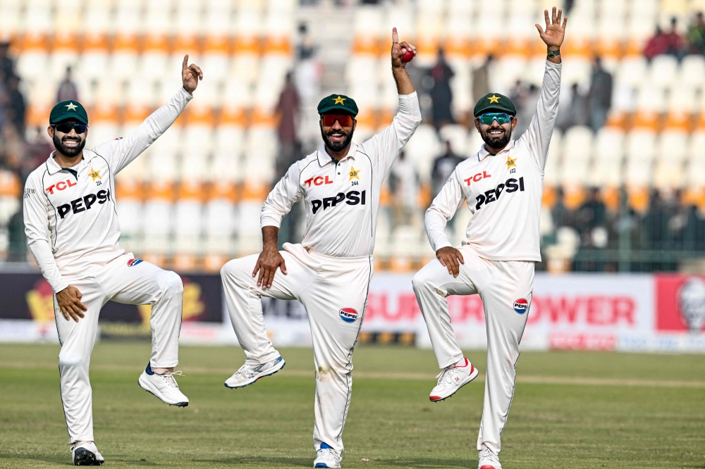 Pakistan's Sajid Khan (C) celebrates with Mohammad Rizwan (L) and Babar Azam after taking a five-wicket haul at the Multan Cricket Stadium in Multan on January 19, 2025. (Photo by Aamir Qureshi / AFP)