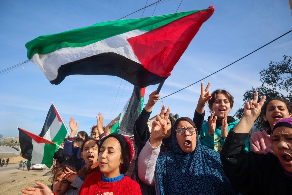 Displaced Palestinians wave national flags as they return to Rafah, in the southern Gaza Strip, on January 19, 2025. (Photo by Eyad Baba / AFP)