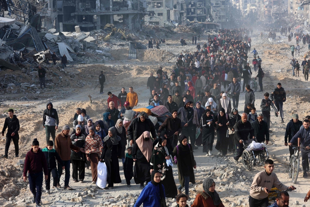 Scores of displaced Palestinians walk along a road in the Saftawi area of Jabalia, as they leave areas near Gaza City where they had taken refuge, toward the further northern part of the Gaza Strip, shortly after a ceasefire deal was expected to be implemented. (Photo by Omar Al-Qattaa / AFP)