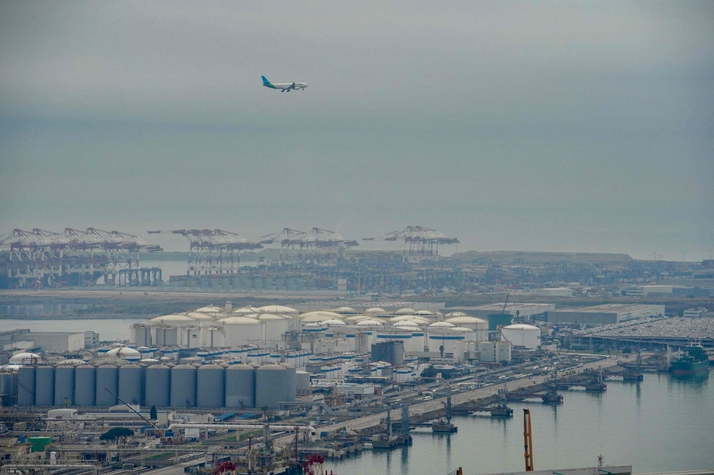 An aeroplane flies over Barcelona's port following an explosion of a tank containing a highly flammable substance in Barcelona on January 21, 2025. (Photo by Manaure Quintero / AFP)
 