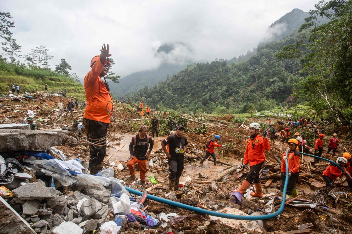 Rescue teams, including Indonesia's National Search and Rescue Agency (BASARNAS), the army, police, and volunteers, use high-pressure water to search for victims of a landslide triggered by heavy rain two days ago, which has so far claimed 19 lives, in Kasimpar Village, Central Java, on January 22, 2025. (Photo by DEVI RAHMAN / AFP)
