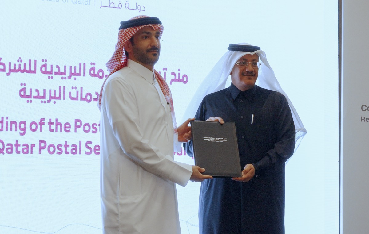 CRA President Engineer Ahmad Abdulla Al Muslemani (left) presenting the license to the Chairman and Managing Director of Qatar Post, Faleh Bin Mohammed Al Naemi during the event yesterday.