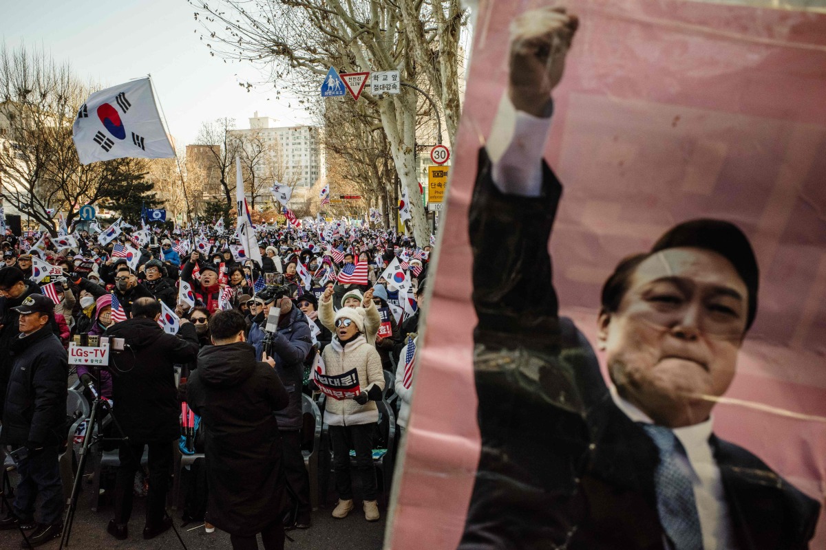 Supporters of South Korea's impeached President Yoon Suk Yeol (pictured on poster R) attend a rally on a road near the Constitutional Court in Seoul on January 23, 2025, after Yoon arrived at the court for hearings that will decide whether to remove him from office. (Photo by ANTHONY WALLACE / AFP)