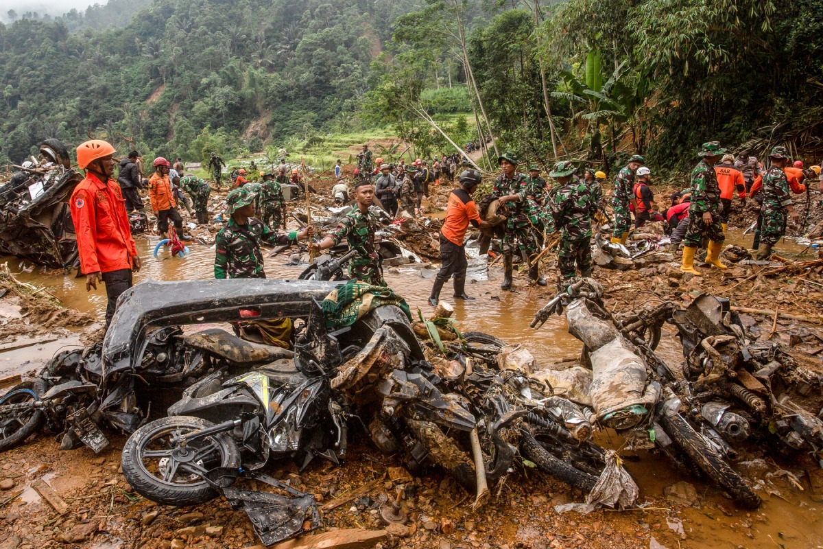 Rescue teams, including Indonesia's National Search and Rescue Agency (BASARNAS) and the Indonesian National Defence Forces (TNI), recover motorcycles from the mud following a landslide triggered by heavy rains in Kasimpar village, Central Java, on January 22, 2025. 