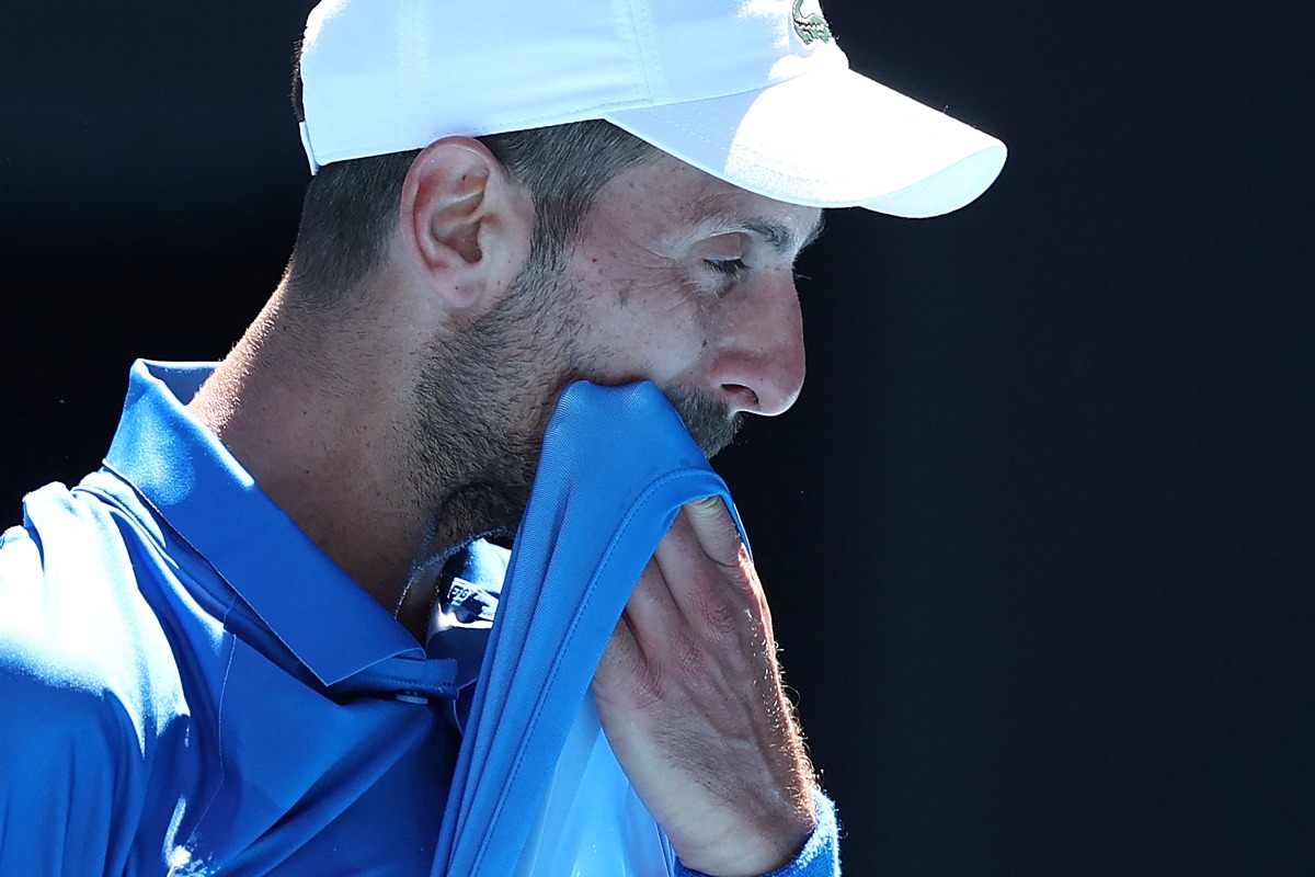 Serbia's Novak Djokovic wipes his face between games during his men's singles semifinal match against Germany's Alexander Zverev on day thirteen of the Australian Open tennis tournament in Melbourne on January 24, 2025. (Photo by Martin KEEP / AFP)