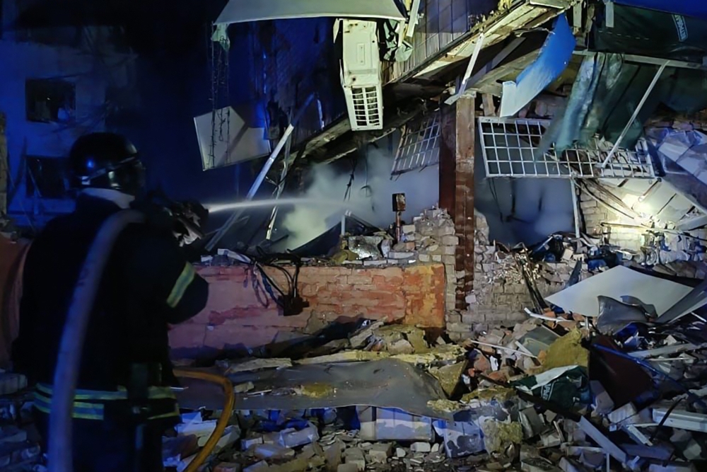 This handout photograph taken and released by the Ukrainian Emergency Service on January 23, 2025, shows a rescuer working with a water hose to extinguish a fire at the site of a missile strike in Zaporizhzhia. (Photo by Handout / Ukrainian Emergency Service  / AFP)