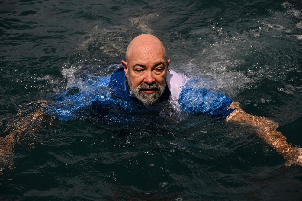 German aerospace engineer Rudiger Koch, 59, jumps into the water to celebrate breaking the Guinness world record on January 24, 2025. (Photo by MARTIN BERNETTI / AFP)