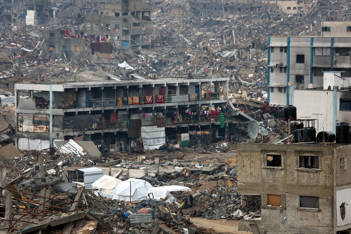 People camp in a heavily damaged UN school surrounded by destruction, as displaced Palestinians return to the northern areas of the Gaza Strip, in Jabalia, on January 23, 2025. (Photo by Omar Al-Qattaa / AFP)