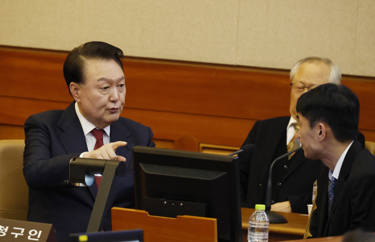 South Korea’s impeached President Yoon Suk Yeol (L) speaks to his lawyers as he attends the fourth hearing of his impeachment trial over his short-lived imposition of martial law at the Constitutional Court in Seoul on January 23, 2025. (Photo by JEON HEON-KYUN / POOL / AFP)