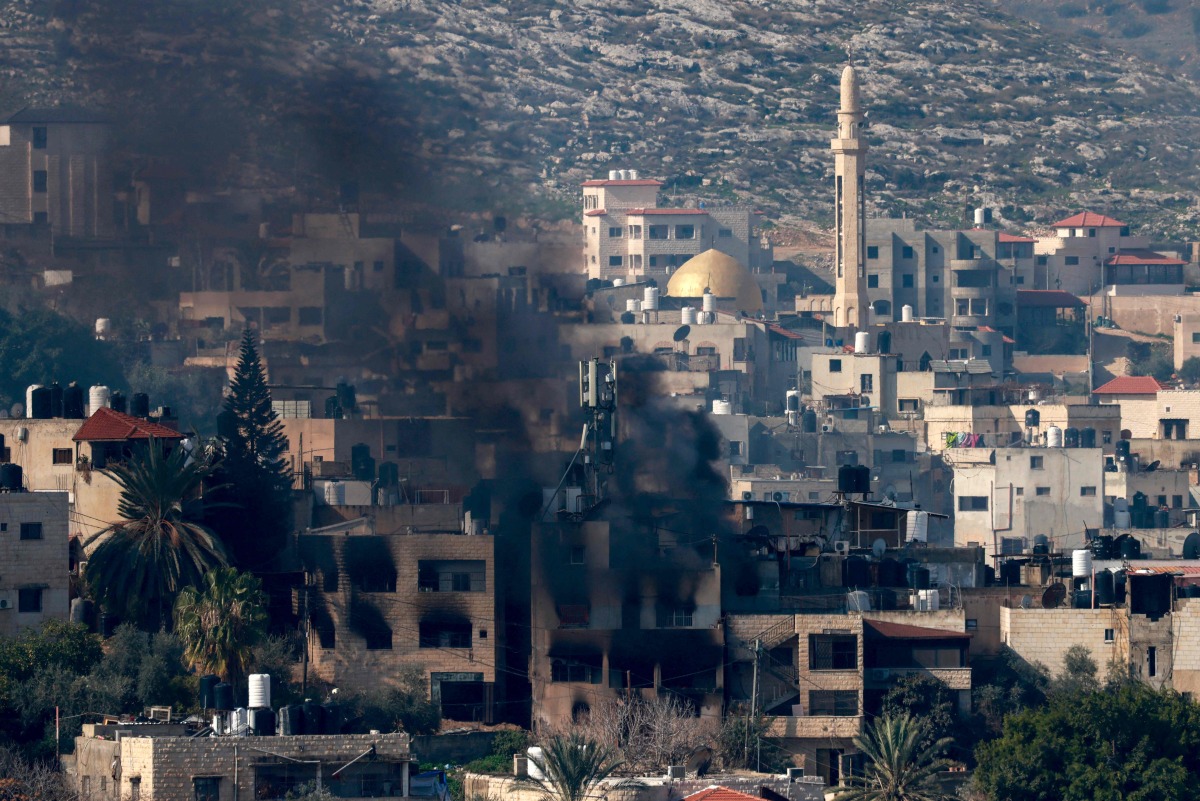 Smoke billows from a burning building during an Israeli raid on the Jenin camp for Palestinian refugees on January 25, 2025. (Photo by Jaafar ASHTIYEH / AFP)
