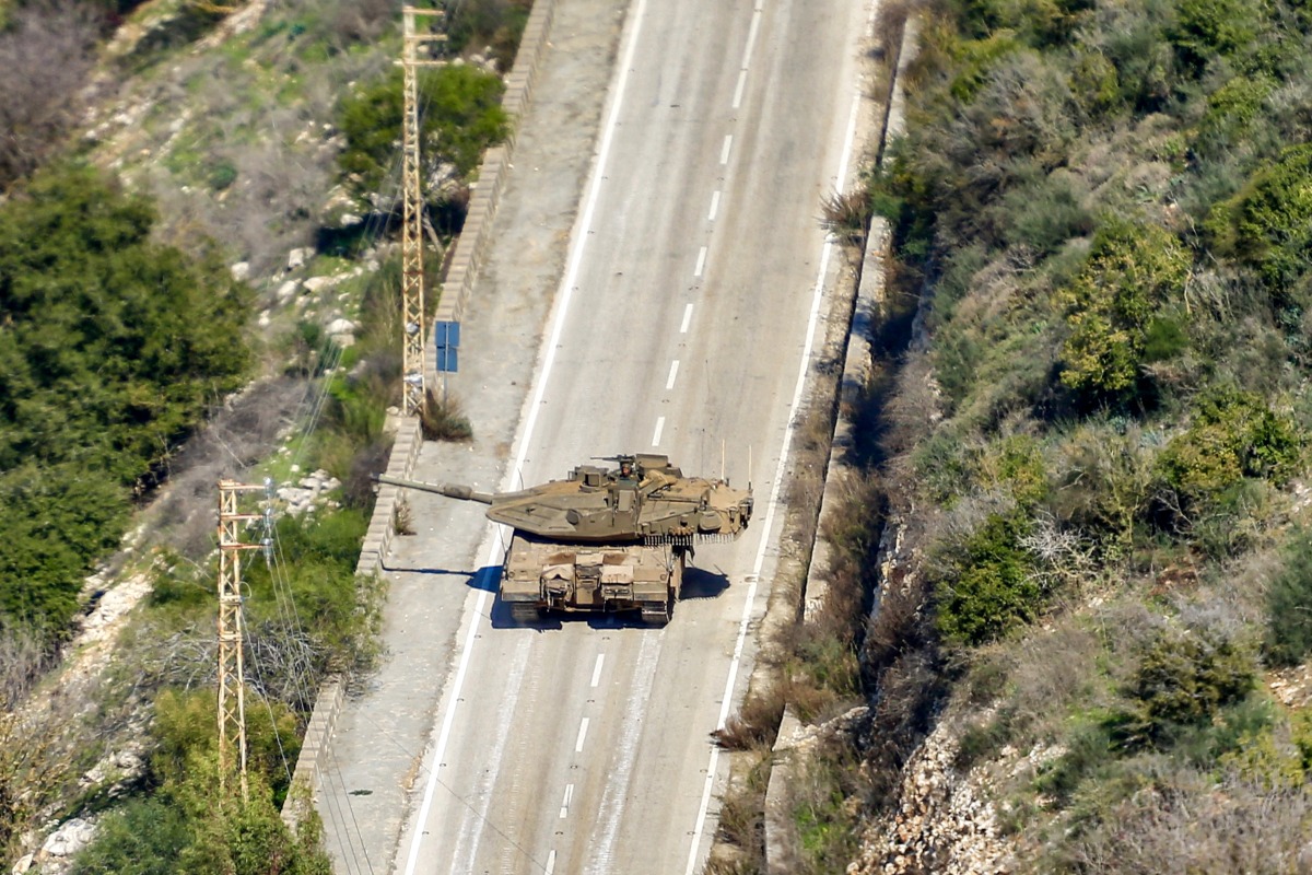 This picture taken from Lebanon's southern village of Shaqra on January 25, 2025 shows an Israeli army Merkava main battle tank moving along a road at the entrance of the village of Hula in south Lebanon. Photo by AFP.
