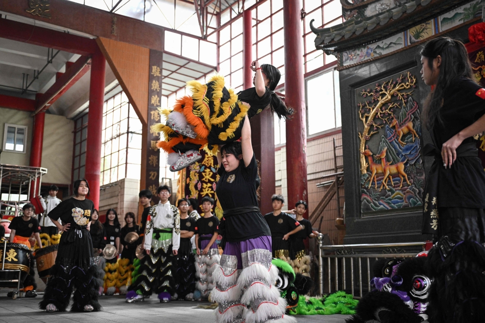 Lin Xinmeng (C) holding a female lion dancer during a practice session at an ancestral temple in Shantou, in southern China's Guangdong province. (Photo by Jade Gao / AFP) 