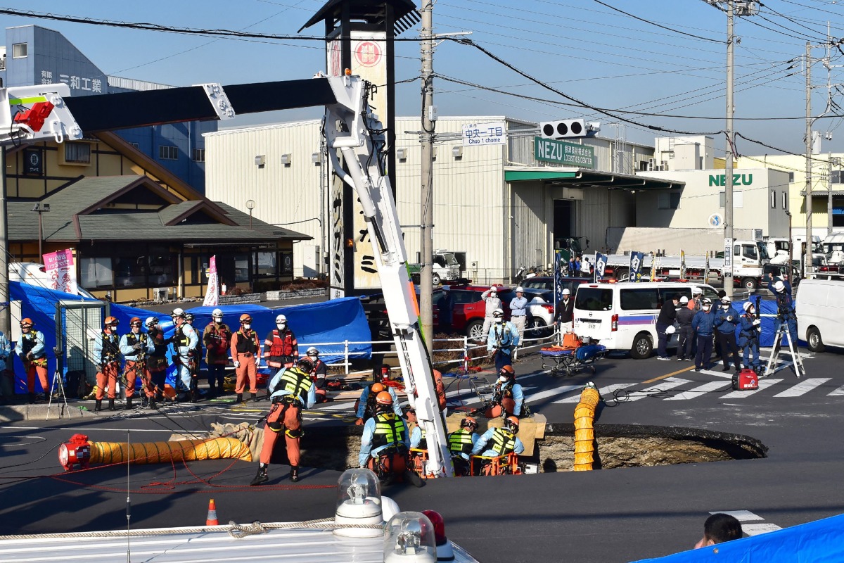 Firefighters work to rescue a truck driver after his vehicle was swallowed up by a sinkhole at a prefectural road intersection, in the city of Yashio, Saitama Prefecture on January 28, 2025. Photo by JIJI Press / AFP